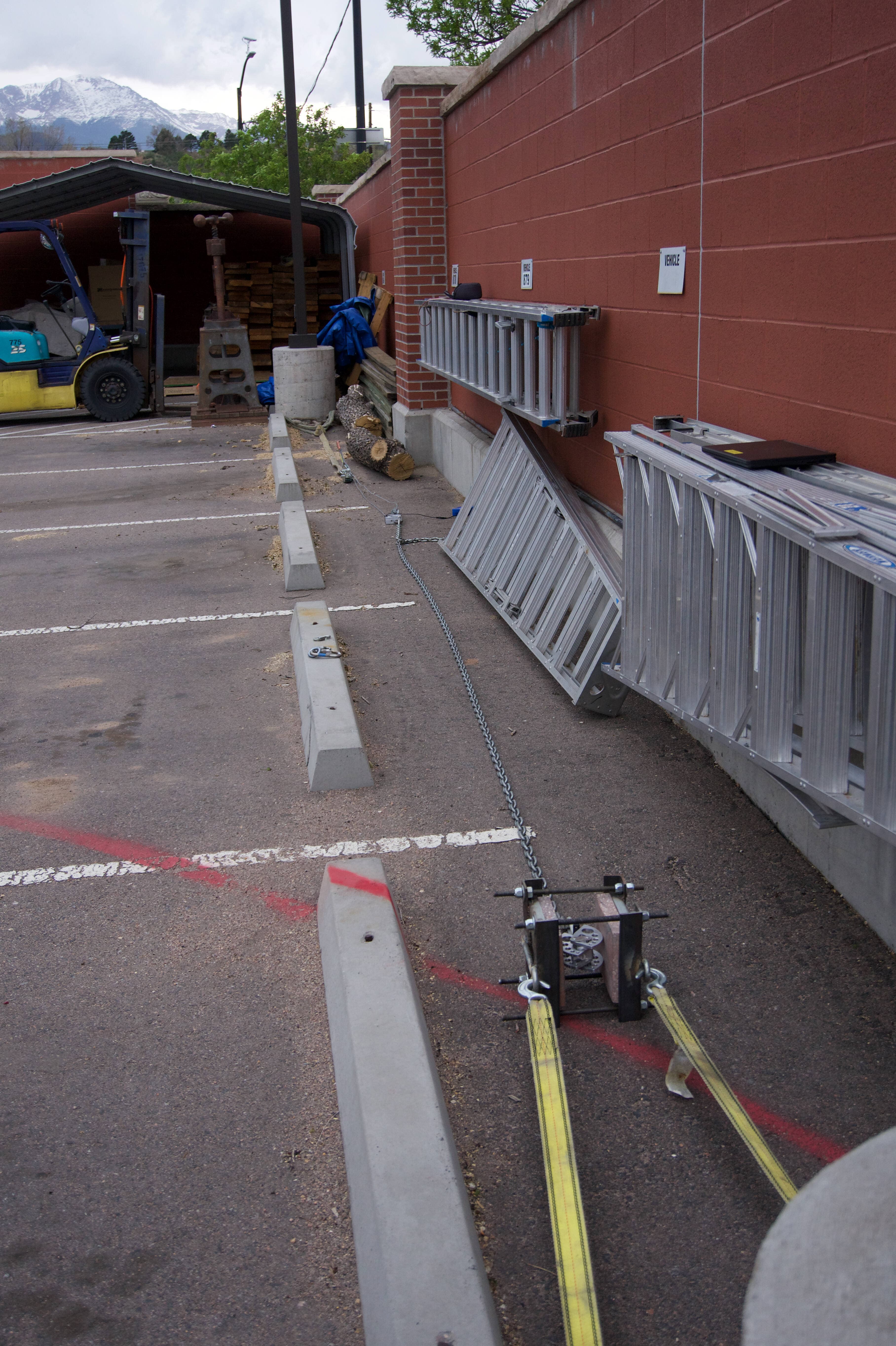 The test setup, strung beteeen the cement base of two light poles. The artificial crack is attached to one pole. The cam is inside it, and leading off on a chain is the force sensor, then the come-along, and then the other light pole.