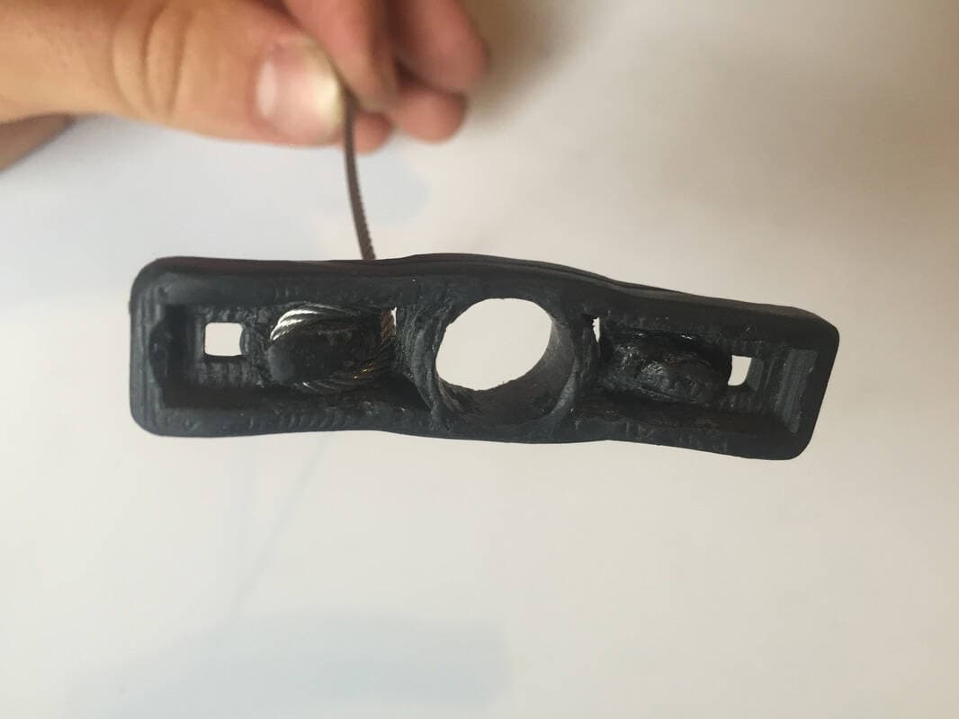 The cable of the trigger wires threaded around the hooks on the bottom of the trigger.